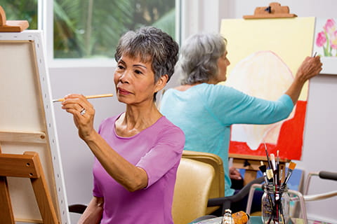 A woman painting in the Vi at La Jolla Village art studio