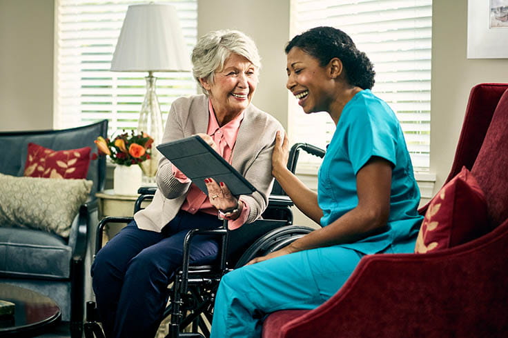 A woman in a wheelchair talks to a care employee.